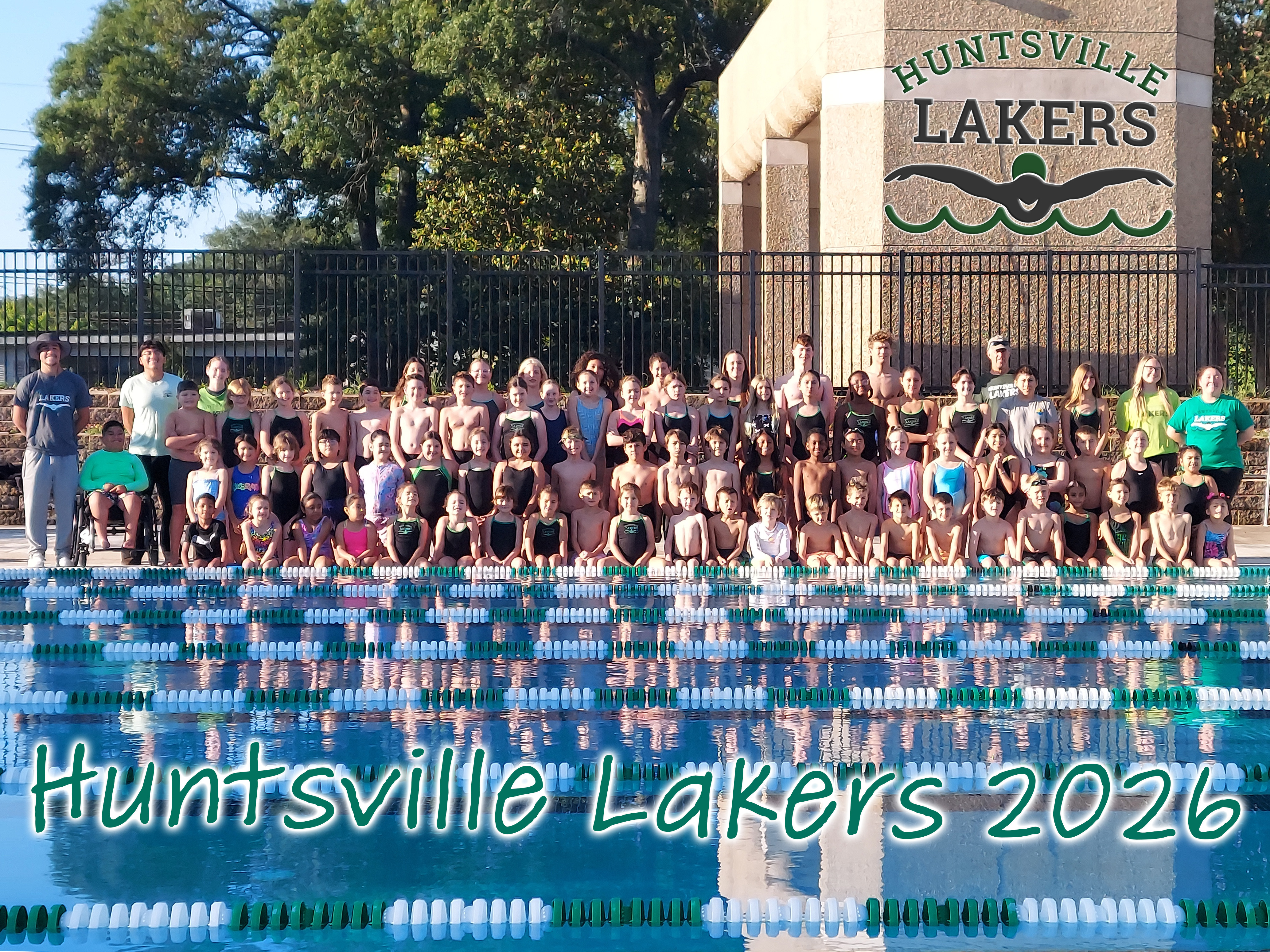 swimmers and coaches pose at pool for team photo