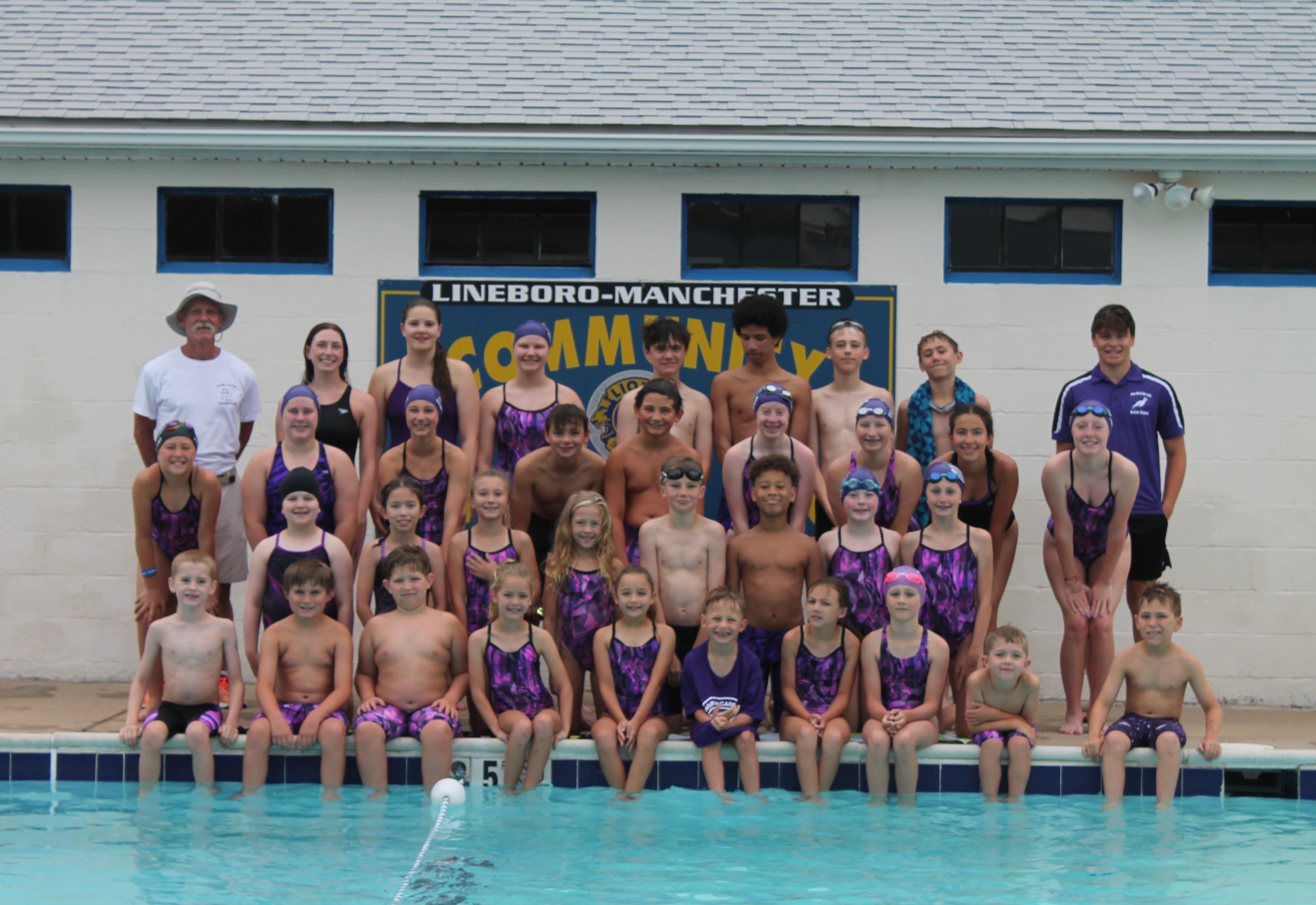 swim team athletes and coaches by a pool