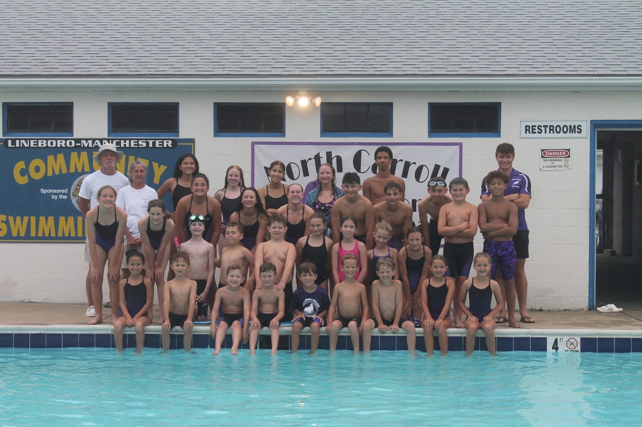 swim team athletes and coaches by a pool