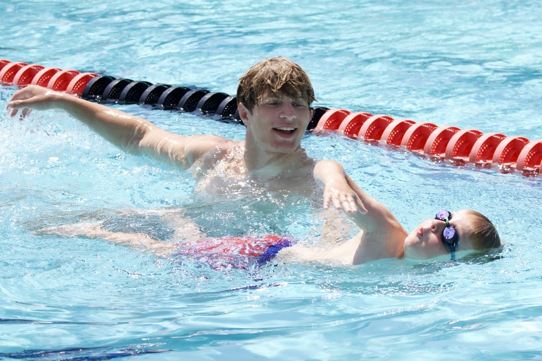 A coach and swimmer in the water practicing Freestyle technique